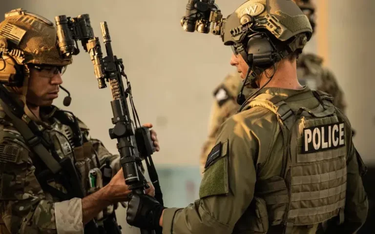 Two tactical officers wearing plate carriers, one with a POLICE patch, during a training exercise | Chase Tactical | Tactical Gear Two Tactical Officers Wearing Plate Carriers, One With A Police Patch, During A Training Exercise