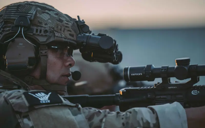 Soldier wearing a tactical headset with boom mic while aiming a rifle | Chase Tactical | Tactical Gear Soldier Wearing A Tactical Headset With Boom Mic While Aiming A Rifle
